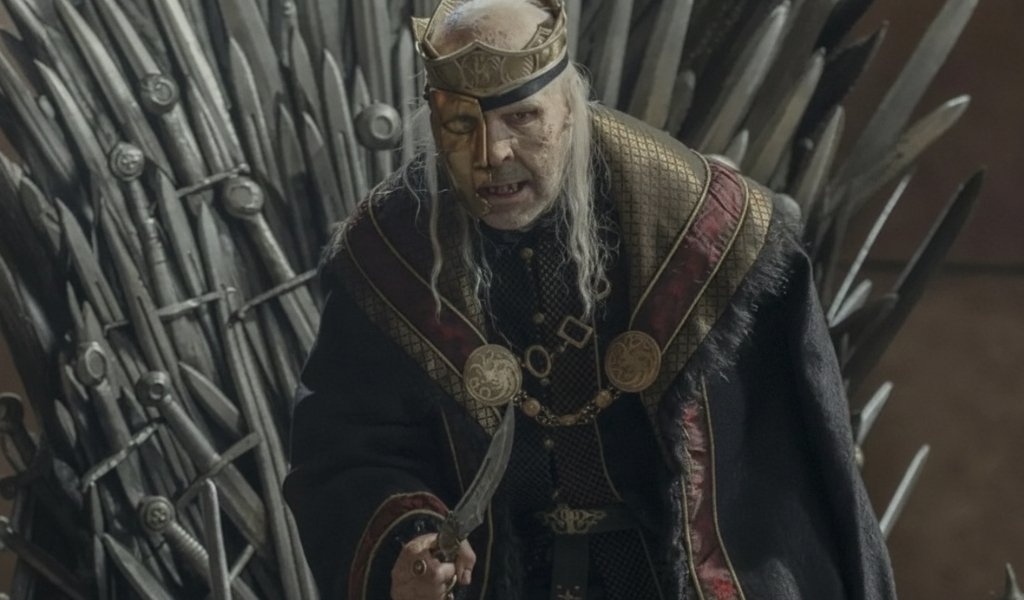 Paddy Considine as King Viserys I Targaryen, wearing his golden mask, sitting on the Iron Throne in House of the Dragon.