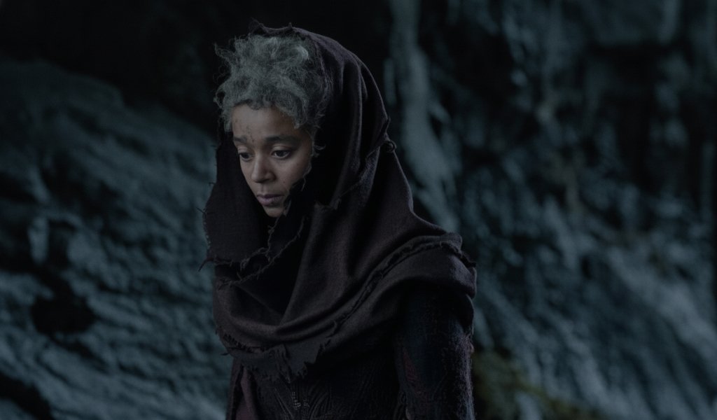 Rhaena Targaryen wearing a dark cloak inside the cave with wild dragon Sheepstealer.